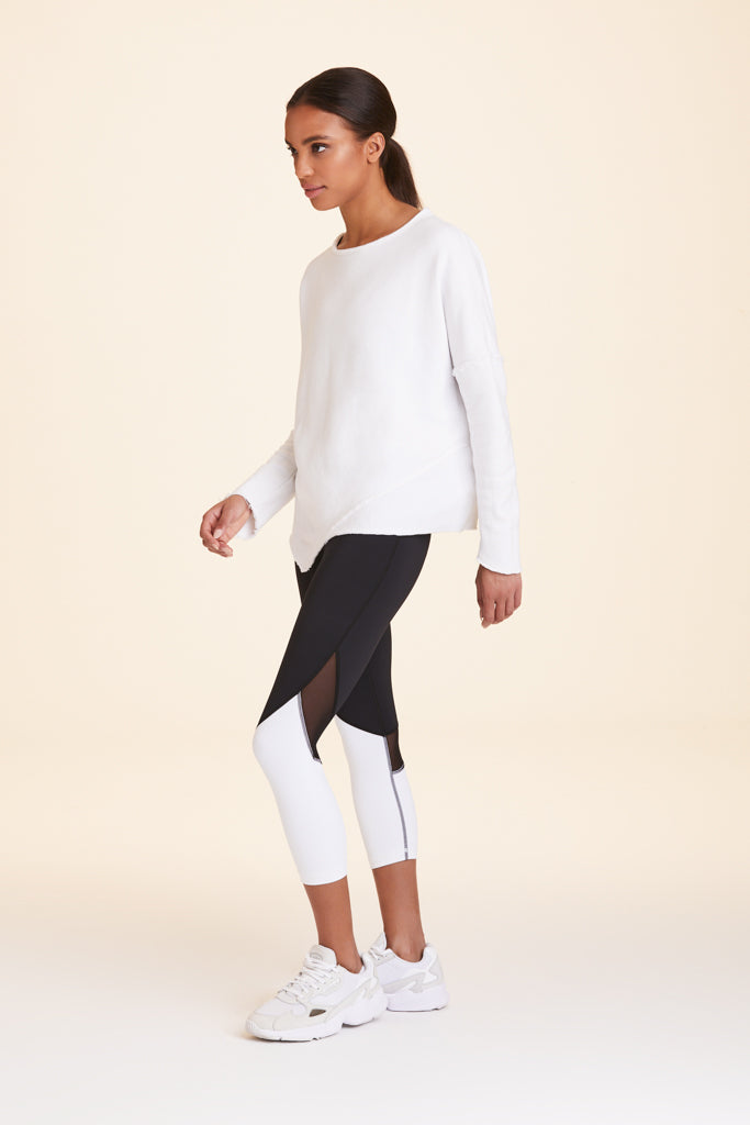 3/4 view of Alala Women's Luxury Athleisure white sweatshirt with distressed details on seams