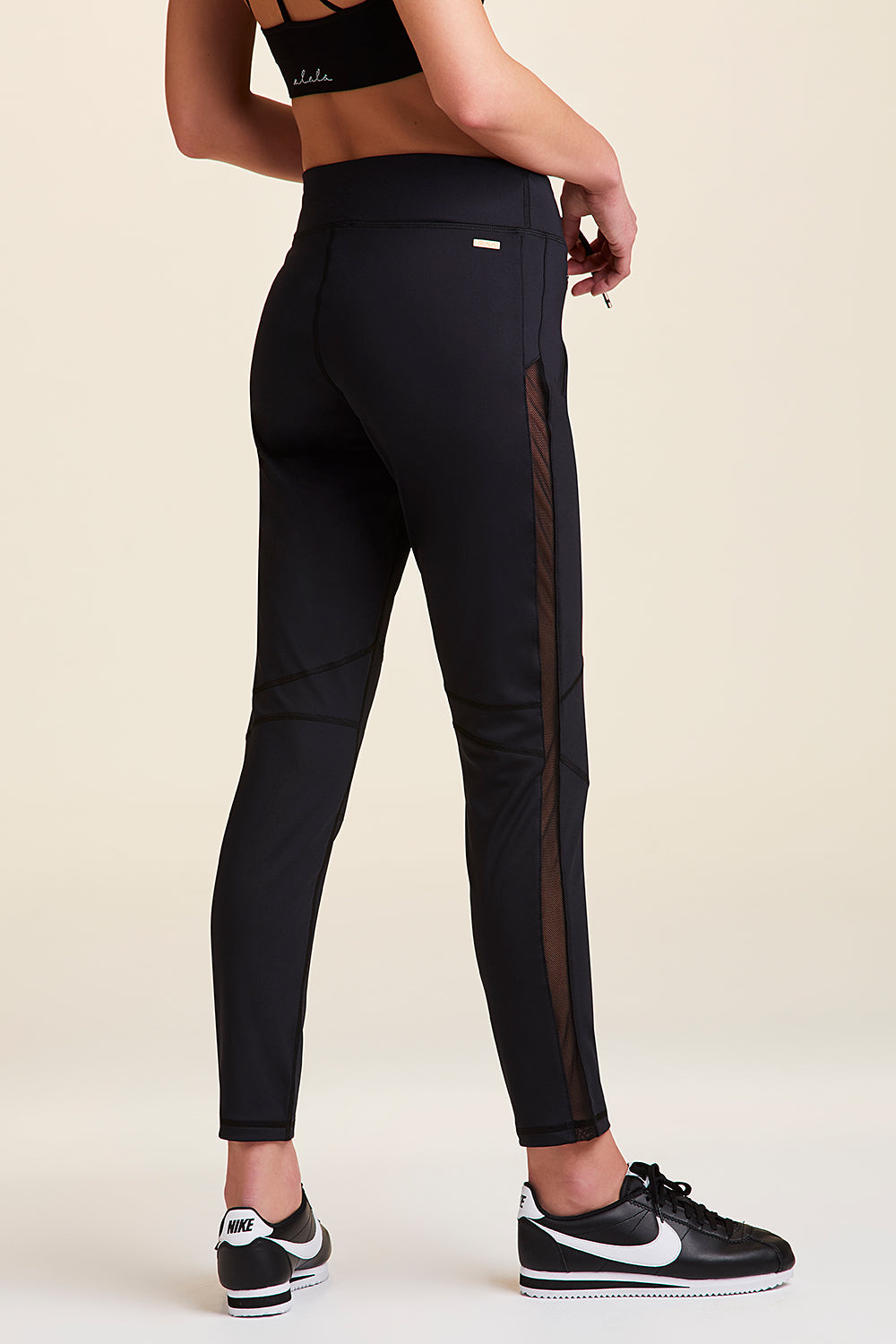 3/4 back view of Alala Women's Luxury Athleisure black sweatpant with sheer mesh side panel