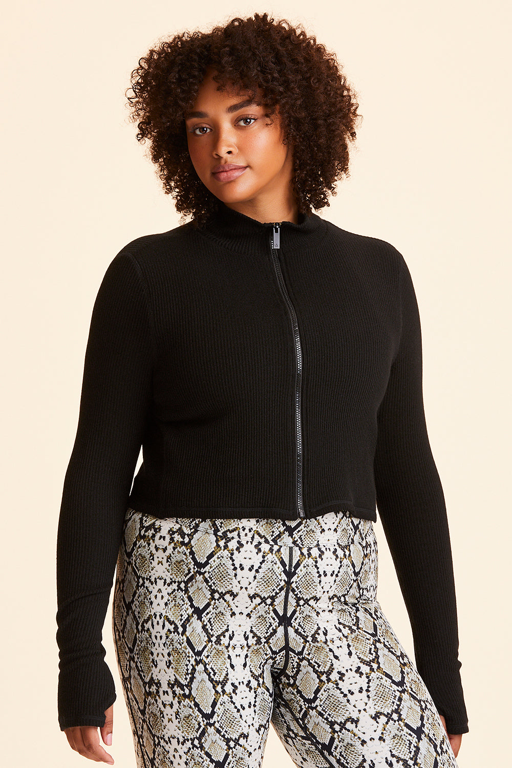 Front view of Alala Women's Luxury Athleisure black ribbed zip up crop jacket in plus size