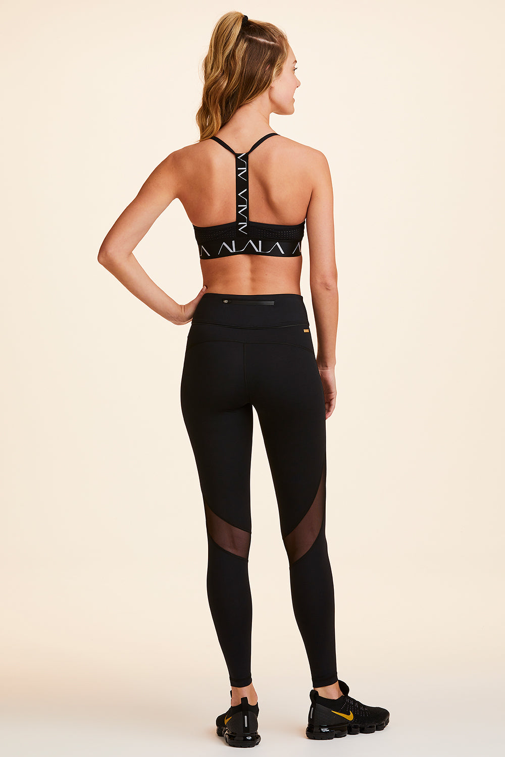 Back view of Alala Women's Luxury Athleisure black tight with mesh paneling on back of knees