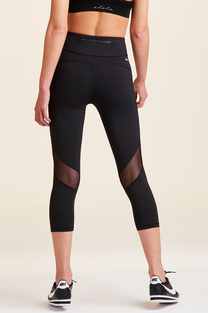 Back view of Alala Women's Luxury Athleisure cropped black tight with mesh paneling on back of knees.