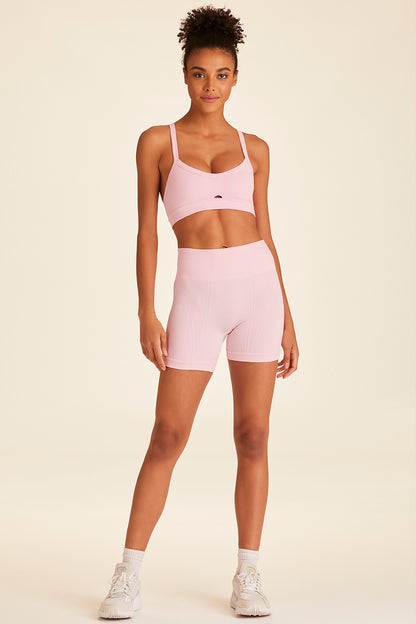 Front full body view of model posing casually while wearing powder pink Barre Cami Bra