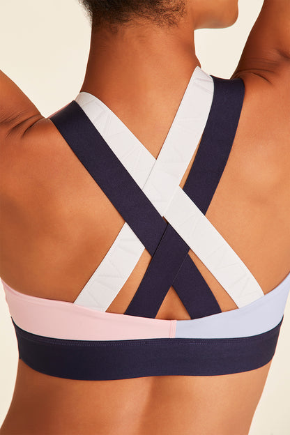 Back closeup of woman with arms above head in navy, pink, and blue Blocked Eclipse Bra showing crossed back straps