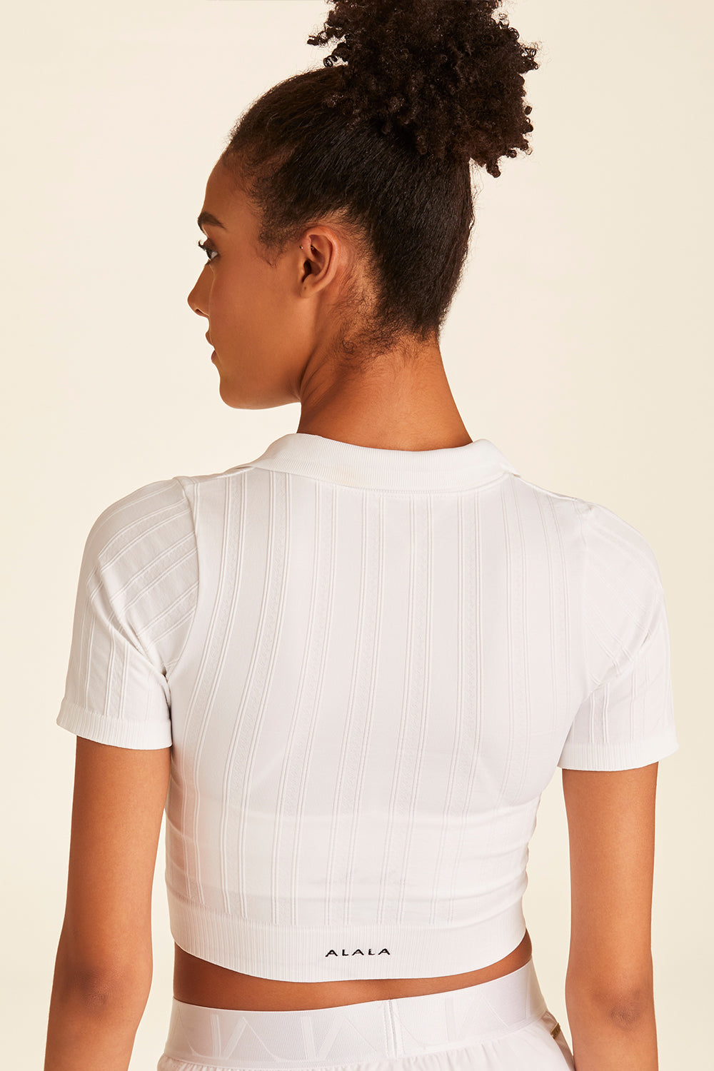 Back closeup view of Alala white Seamless Polo while model looks to the side