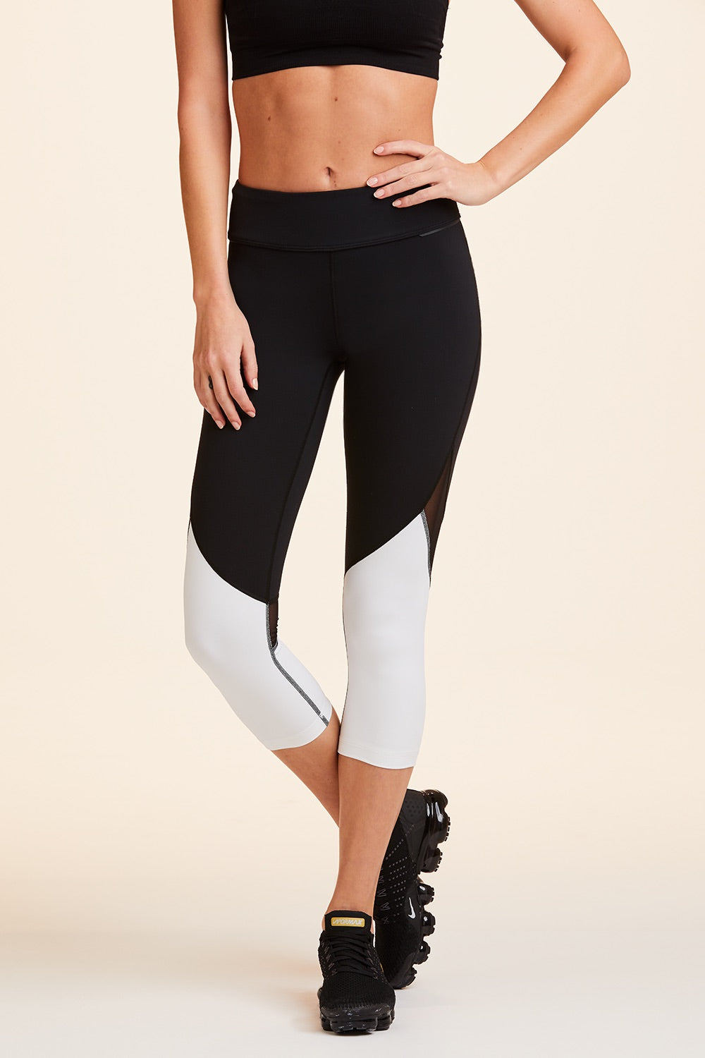 Front view of Alala Women's Luxury Athleisure cropped black and white tight with mesh paneling on back of knees.