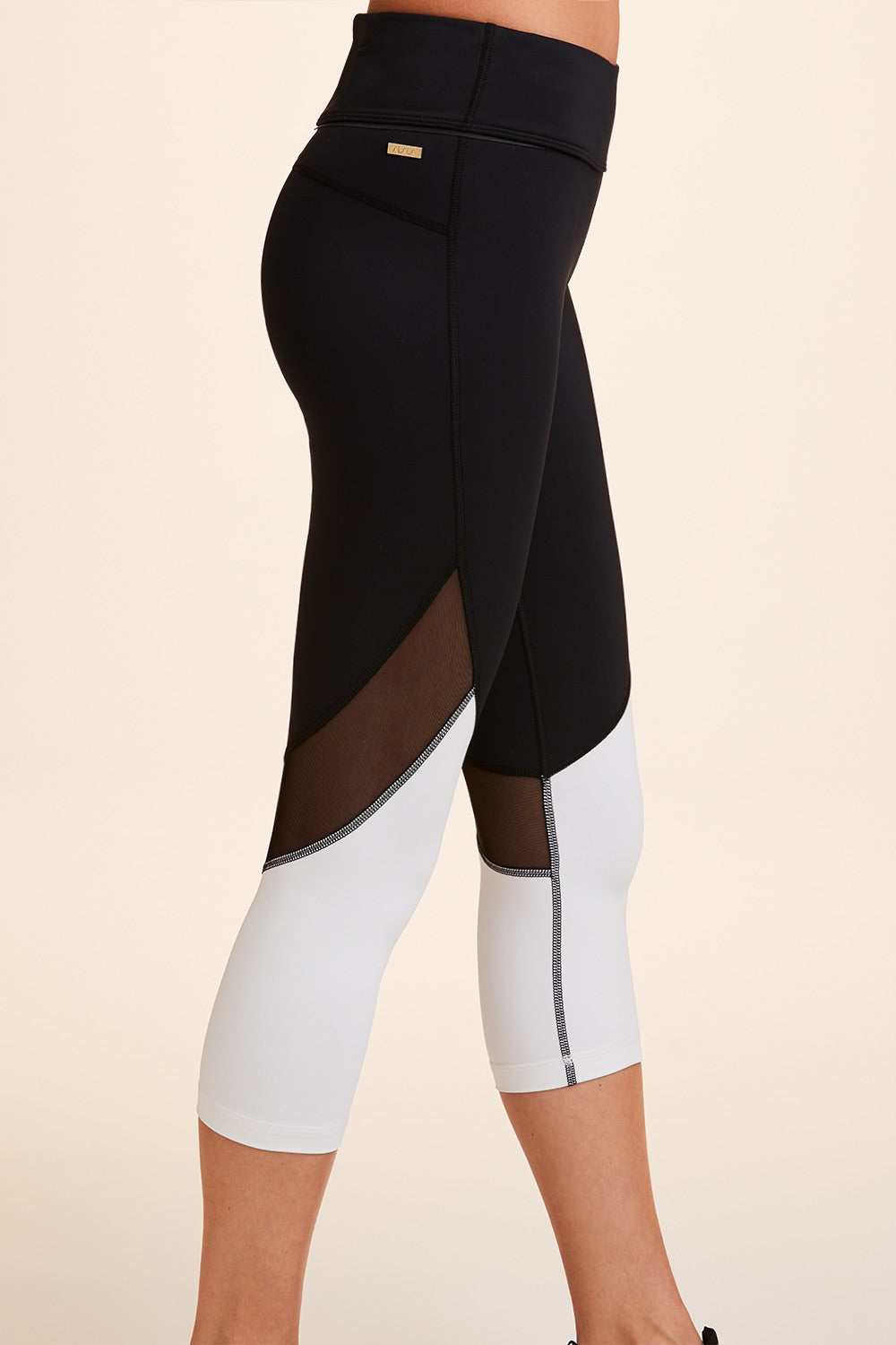 Side view close-up of Alala Women's Luxury Athleisure cropped black and white tight with mesh paneling on back of knees.