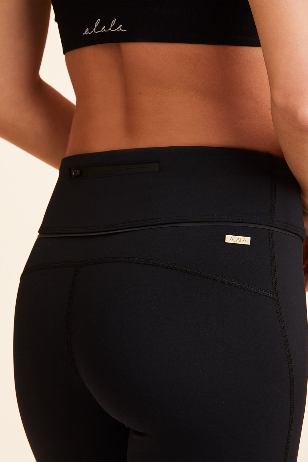 Back view close-up  of Alala Women's Luxury Athleisure cropped black and white tight with mesh paneling on back of knees.