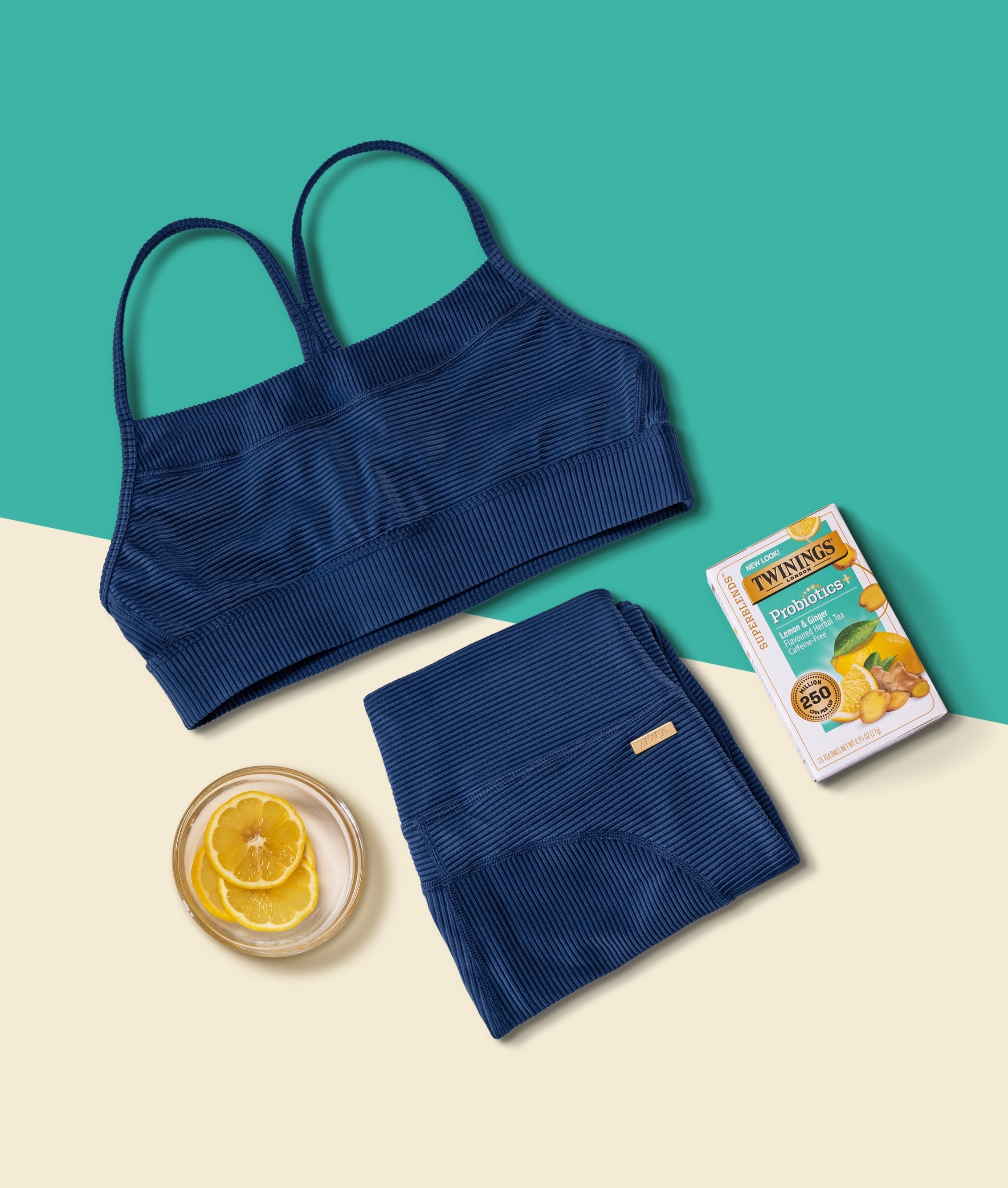 Twinings Probiotic Lemon Tea alongside neatly folded Alala's "Raya Rib set" in navy. 