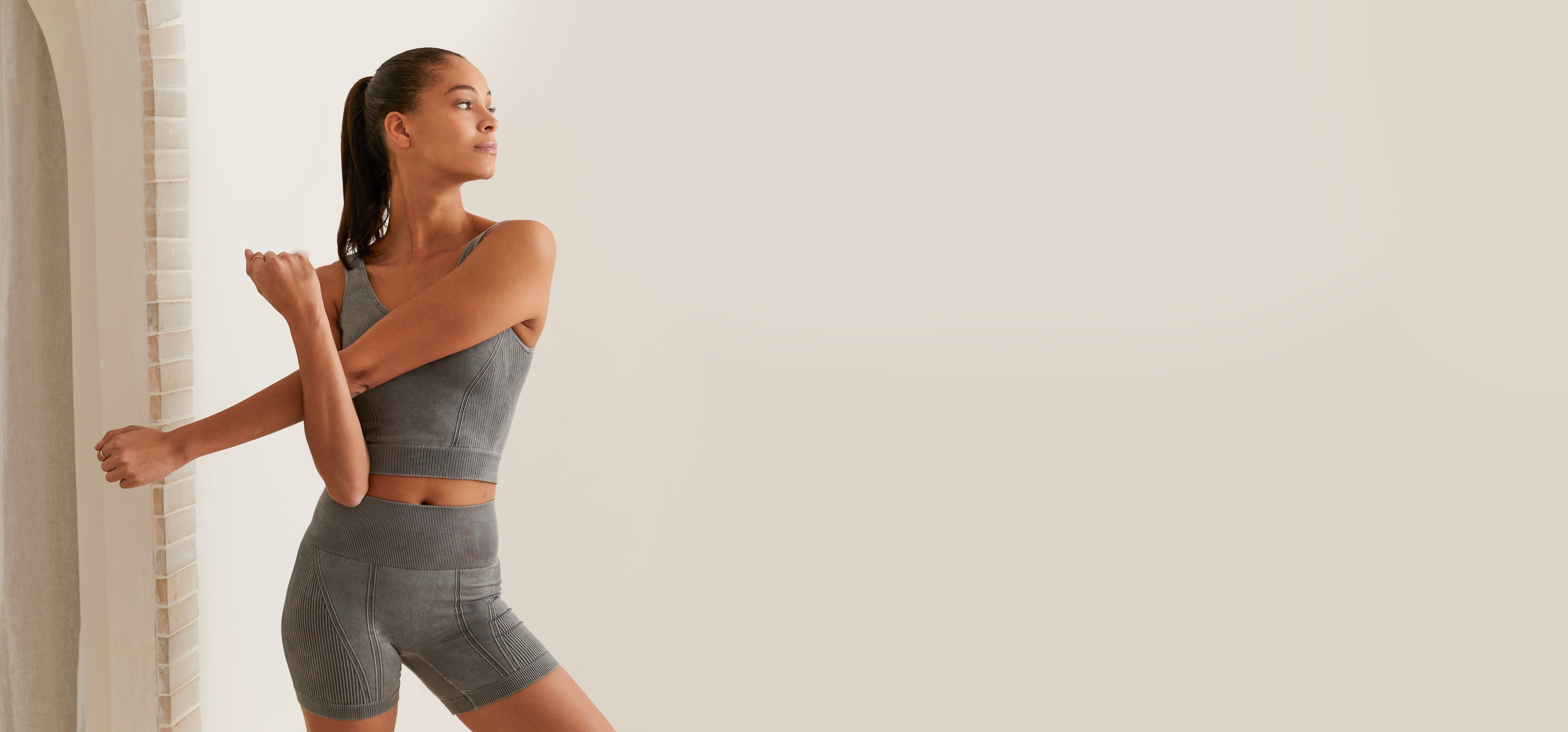 A women stretching in the "Barre Seamless Set" in grey.