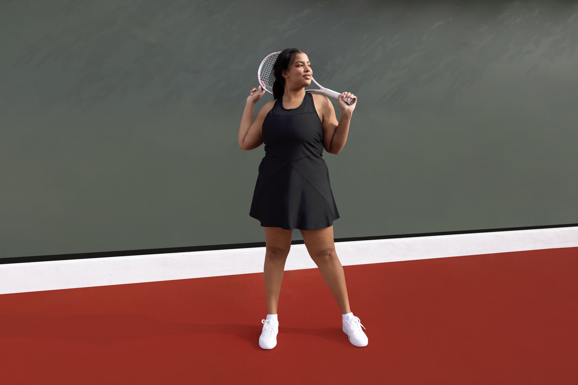 Someone wearing the black "Serena Dress" on a tennis court. 