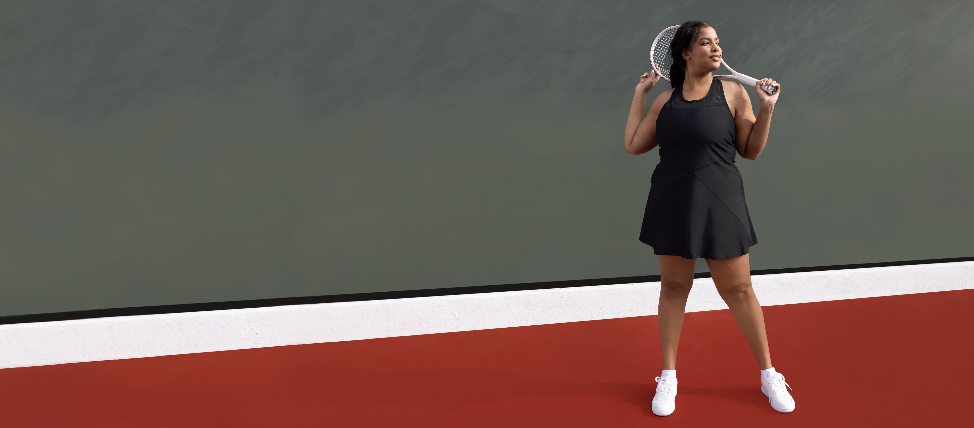 Someone wearing the black "Serena Dress" on a tennis court. 