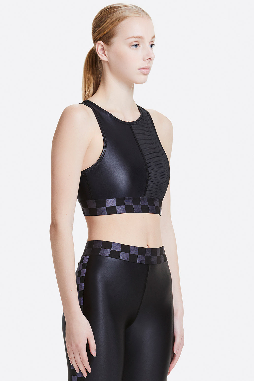 3/4 view of Alala Women's Luxury Athleisure black shiny/mesh sports bra with checkered waistband