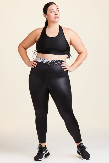 Front view of Alala Women's Luxury Athleisure shiny black tight with black and white polda dot detail on waistband and side seams in plus size