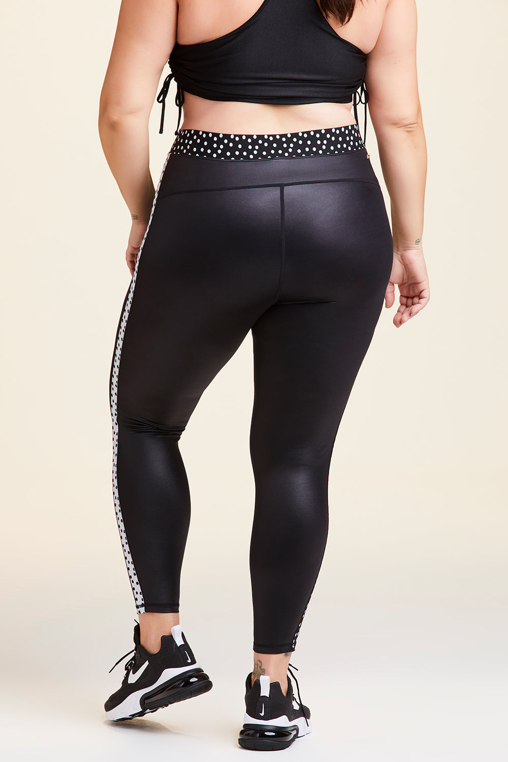 Back view of Alala Women's Luxury Athleisure shiny black tight with black and white polda dot detail on waistband and side seams in plus size