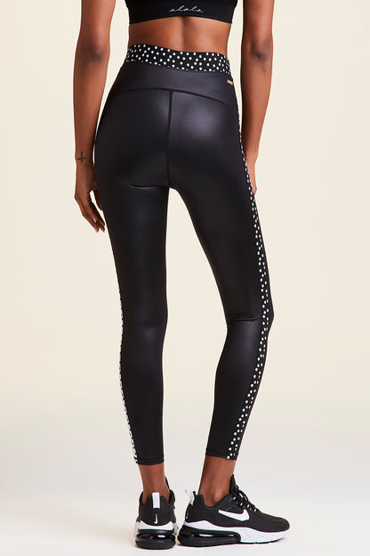 Back view of Alala Women's Luxury Athleisure shiny black tight with black and white polda dot detail on waistband and side seams