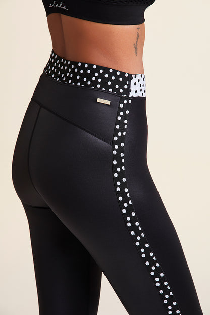 3/4 back close-up view of Alala Women's Luxury Athleisure shiny black tight with black and white polda dot detail on waistband and side seams