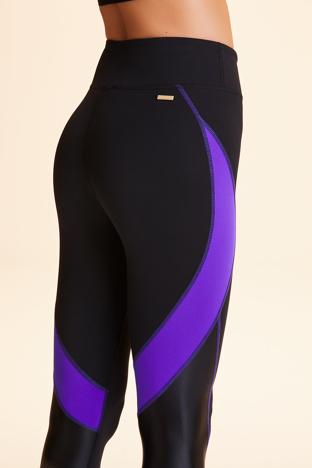 Close-up side view of Alala Women's Luxury Athleisure black and purple color-blocked tight