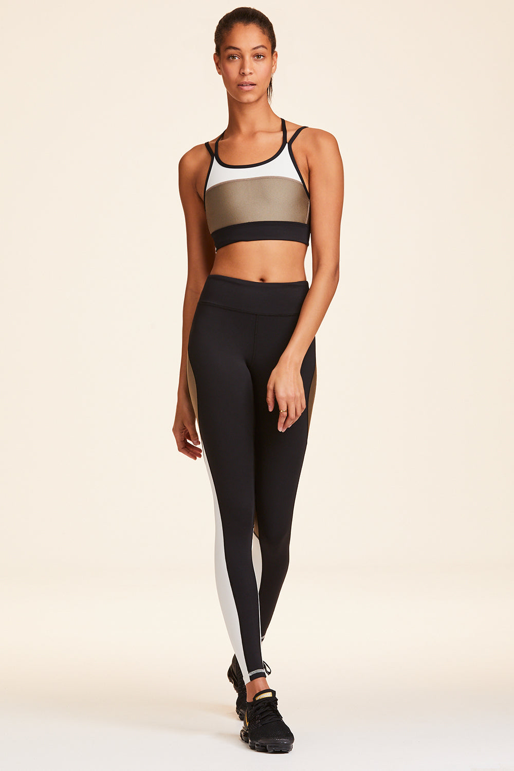 Full frontal view of Alala Women's Luxury Athleisure blocked sports bra with criss-crossed straps in gold, white, & black