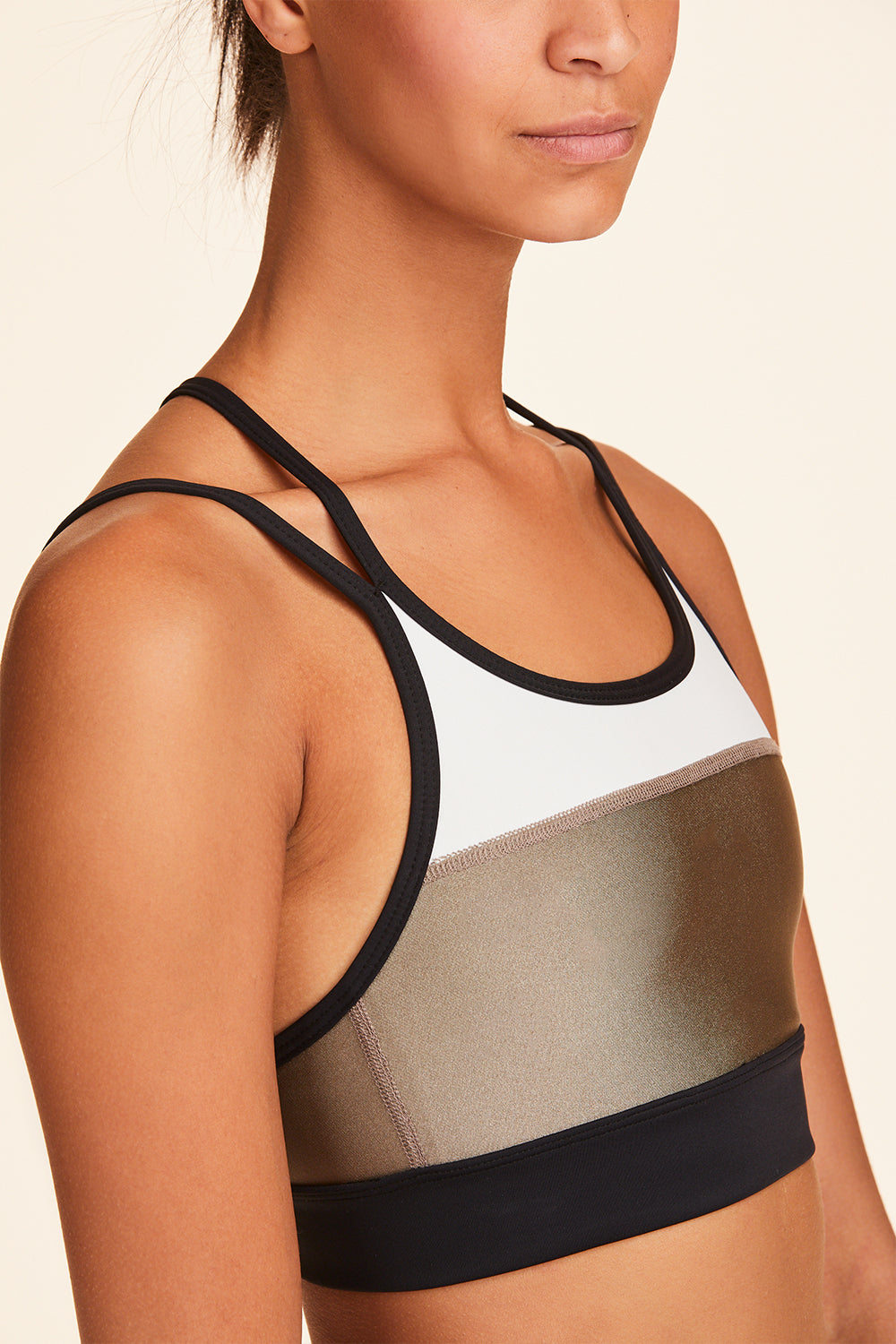3/4 view of Alala Women's Luxury Athleisure blocked sports bra with criss-crossed straps in gold, white, & black