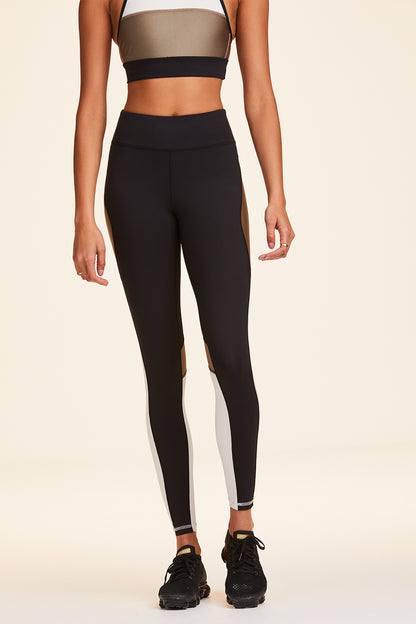 Front view of Alala Women's Luxury Athleisure black, white, and gold color-blocked tight