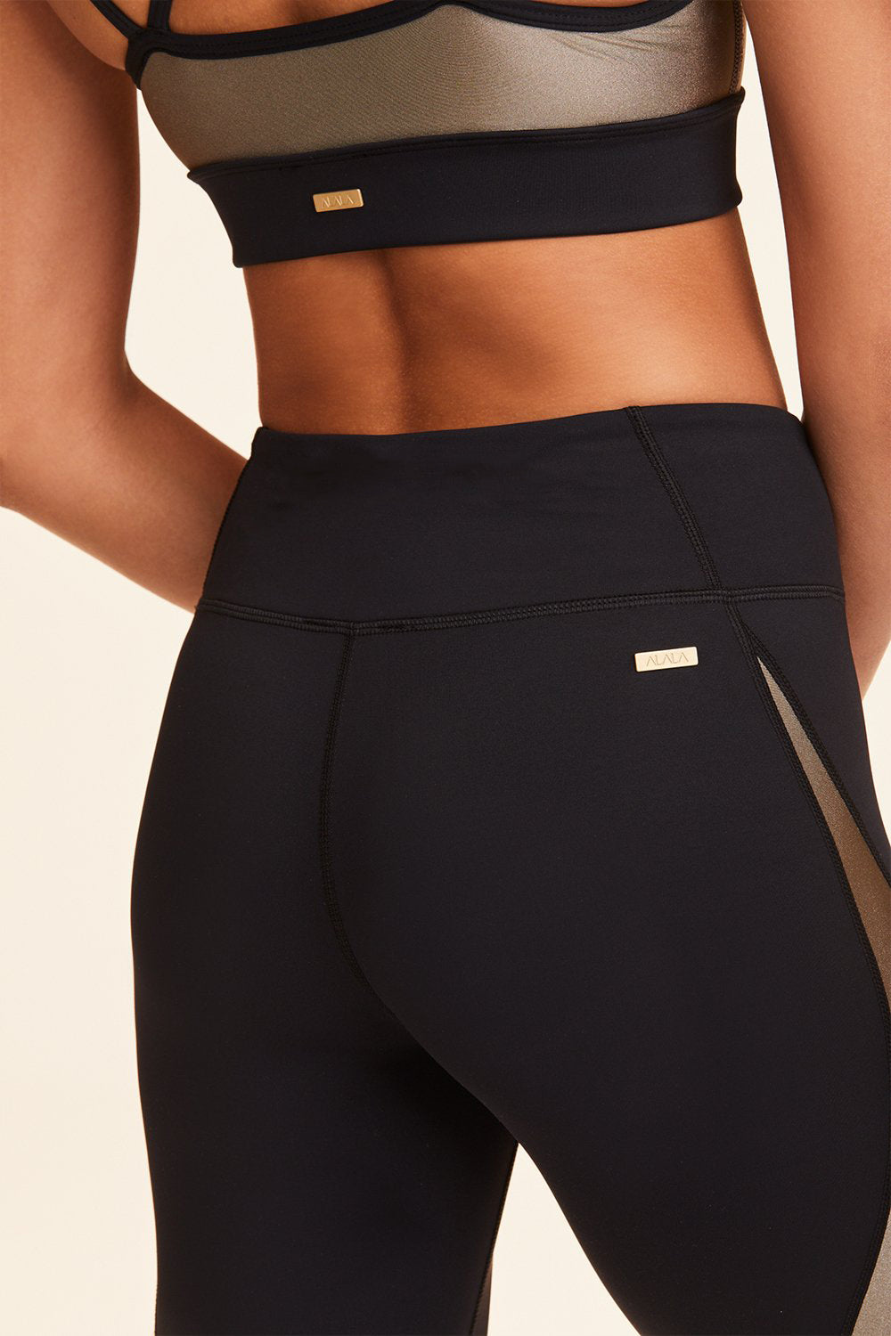 Close-up back view of Alala Women's Luxury Athleisure black, white, and gold color-blocked tight