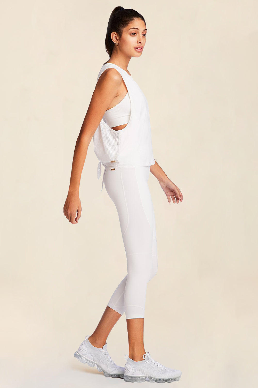 Side full body view of Alala Women's Luxury Athleisure mesh tie back tank in white