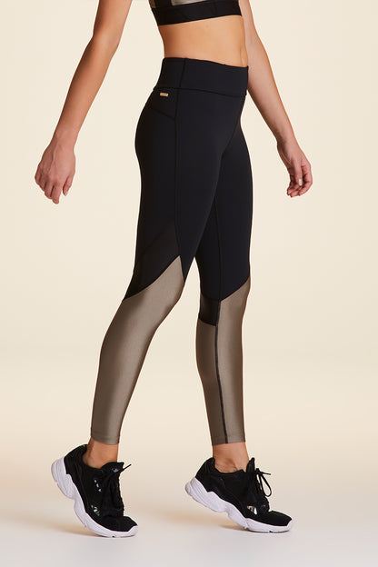 Side view of Alala Luxury Women's Athleisure captain ankle tight in black and gold dust