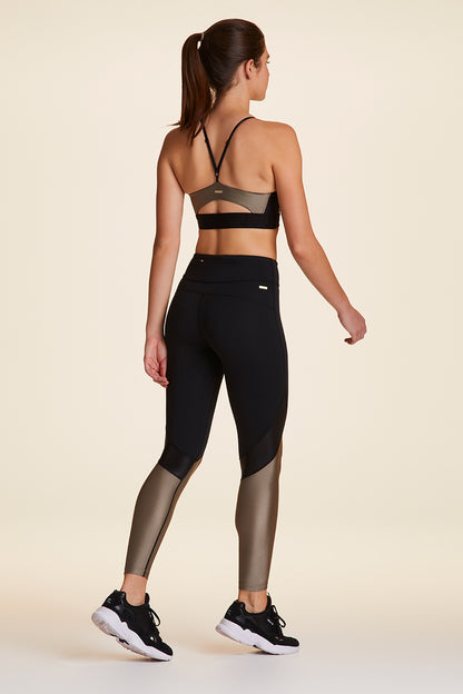 Full body back view of Alala Luxury Women's Athleisure captain ankle tight in black and gold dust