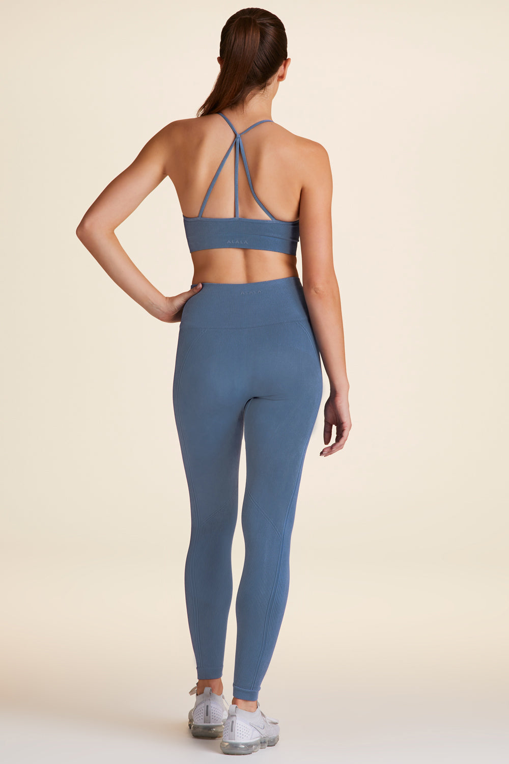 Full body back view of Alala Luxury Women's Athleisure blue barre bra with cross over back strap detailing