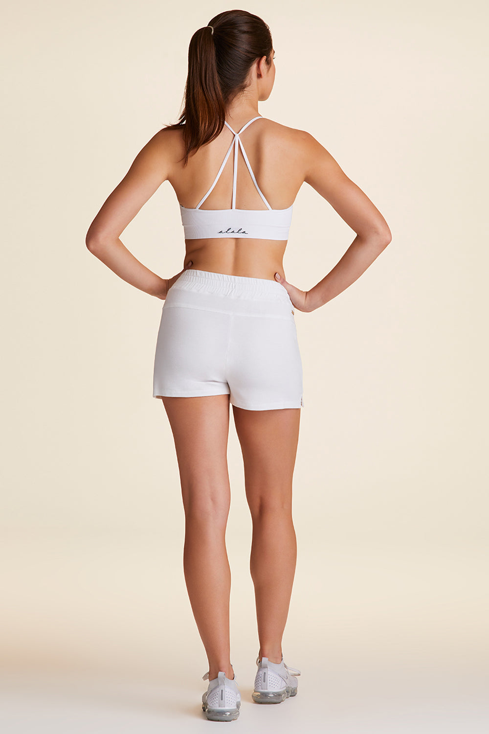 Back full body view of Alala Luxury Women's Athleisure plie short in bone with front pockets
