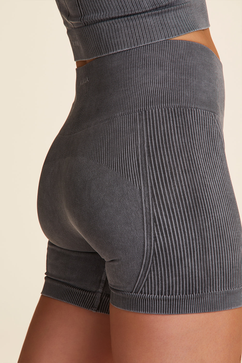 Zoomed in view of Alala Luxury Women's Athleisure barre seamless short in grey with signature Alala detail on back hem
