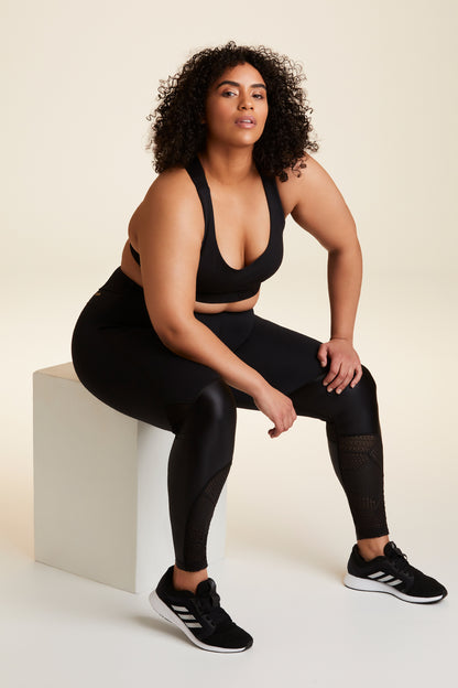 Model sitting in Alala Luxury Women's Athleisure collage tight in black