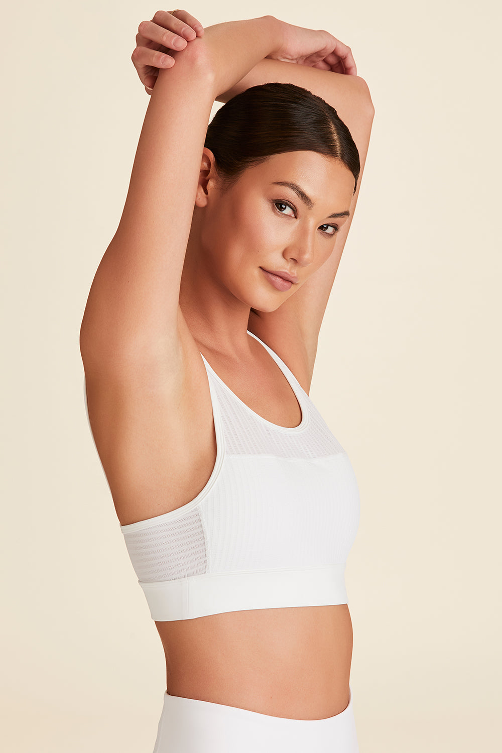 Side view of model with arms above head in white Mirage Cami Bra with breathable side fabric visible