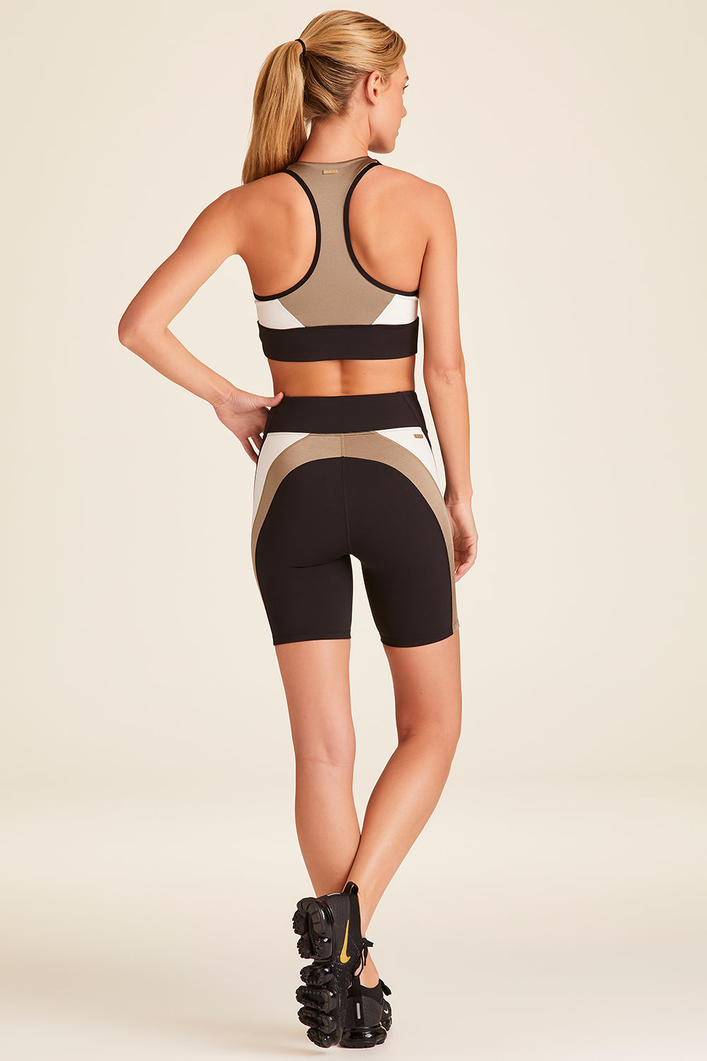 Full body back view of Alala Luxury Women's Athleisure bolt short in black, gold, and bone