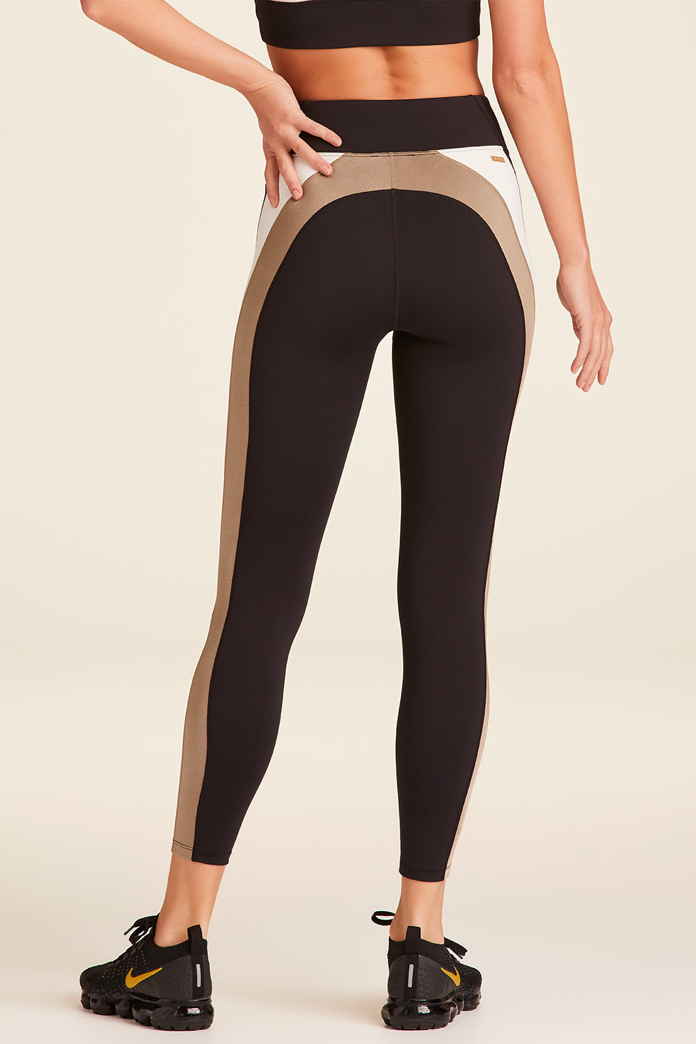 Back view of Alala Luxury Women's Athleisure bolt tight in black, gold, and bone