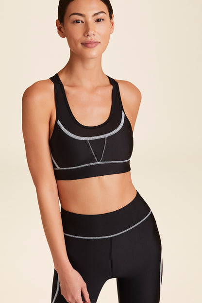 Front view of Alala Women's Luxury Athleisure black sports bra with white surf-inspired stiching