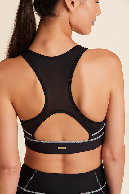 Back view of Alala Women's Luxury Athleisure black sports bra with white surf-inspired stiching