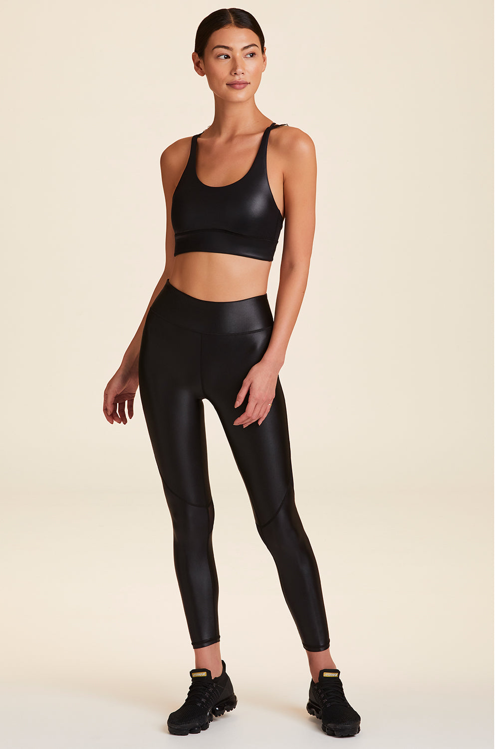 Front full body view of Alala Women's Luxury Athleisure ribbon bra in black liquid black with ribbon detailing on straps