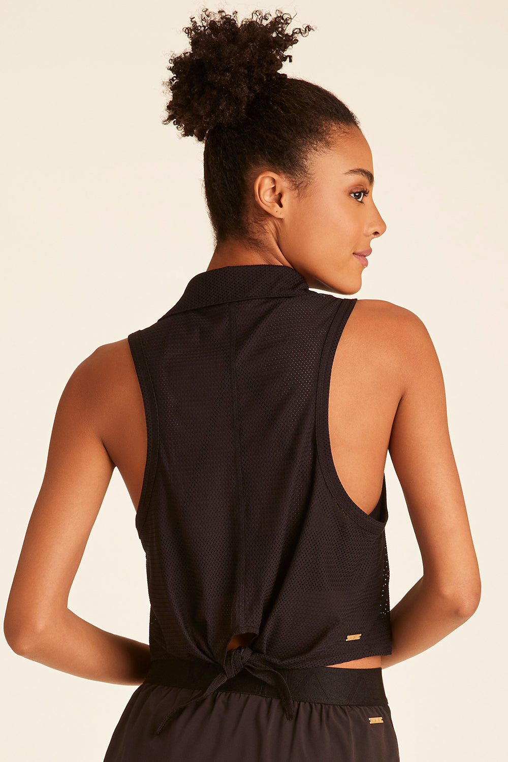 Back view of woman with arms crossed showing back tie detailing of black Tie Back Polo