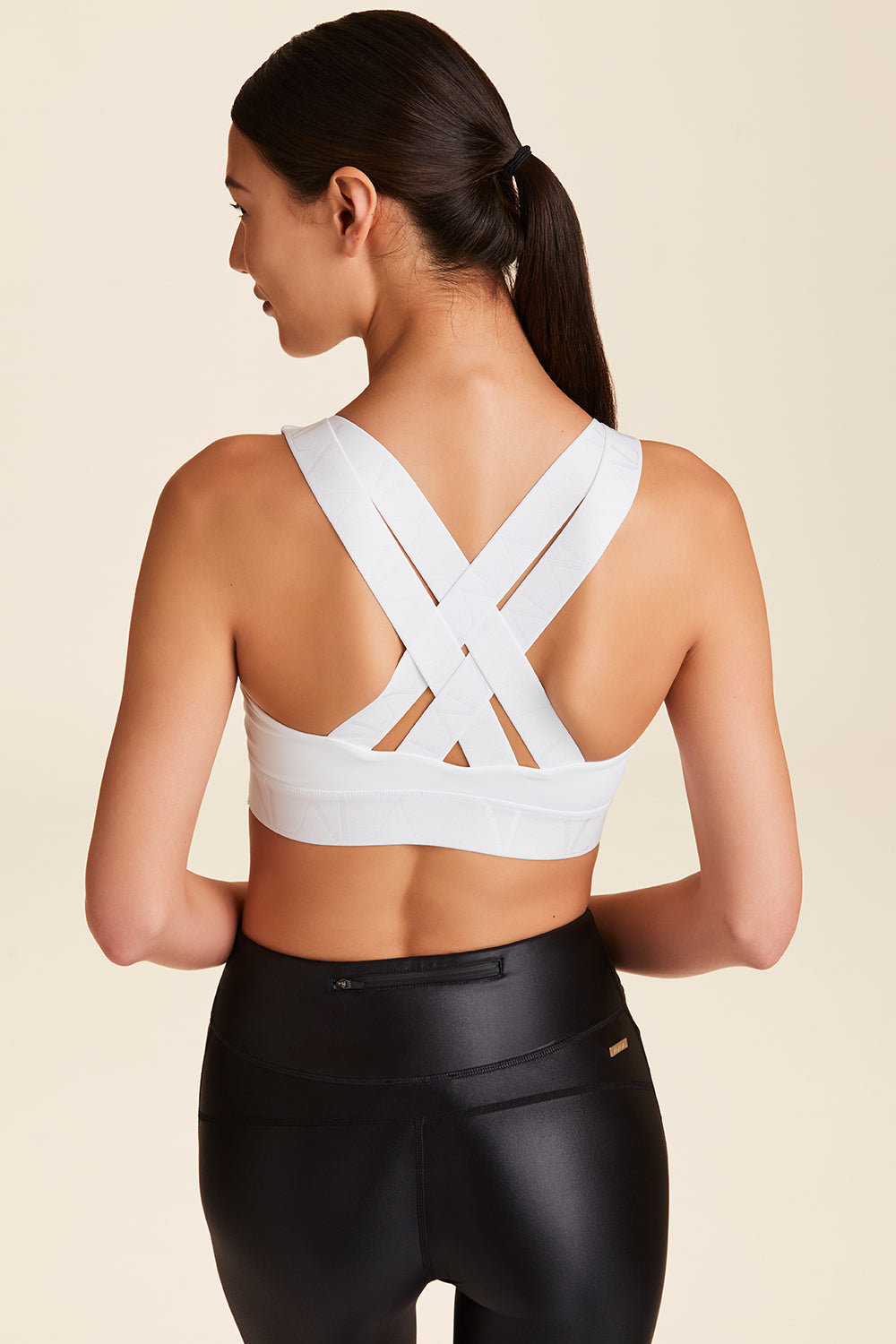 Back view of Alala Women's Luxury Athleisure white sports bra with cross back straps
