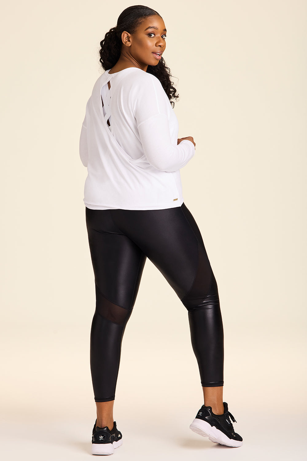 Back view of Alala Women's Luxury Athleisure shiny black tight with mesh paneling on back of knees in plus size