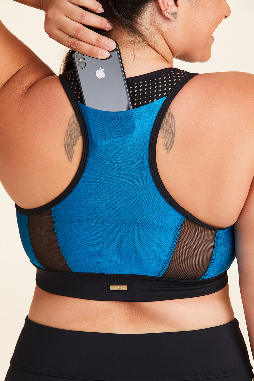 Back view of Alala Women's Luxury Athleisure black and teal sports bra with mesh detail in plus size