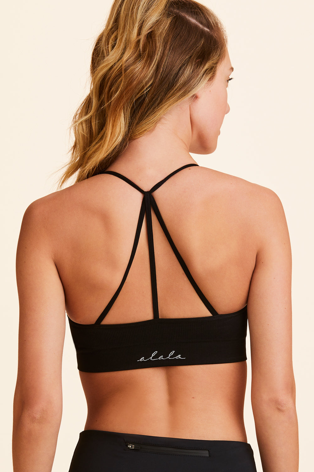 Back view of Alala Women's Luxury Athleisure black seamless bra with cross over back strap detailing