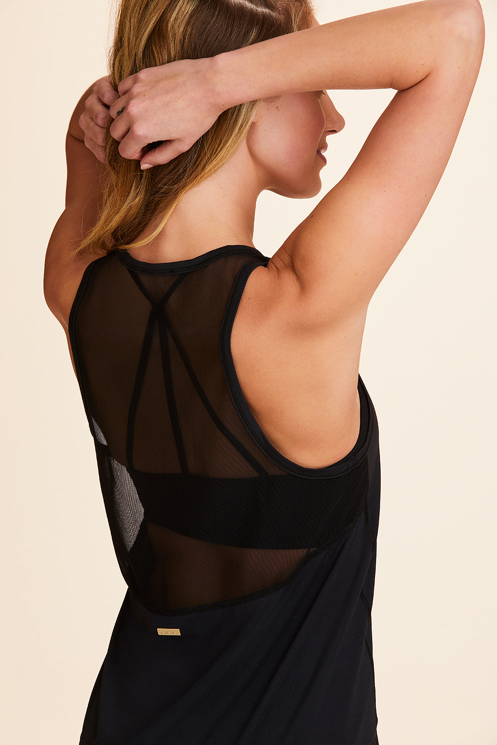 3/4 back view of Alala Women's Luxury Athleisure black tank with black mesh detail